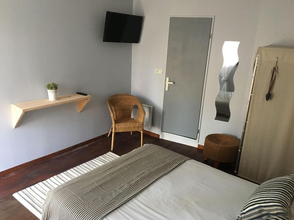 a bedroom with a bed and a chair and a mirror at Le Pavillon Bleu in Cap-Ferret