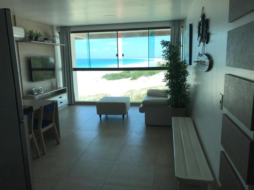 a living room with a couch and a large window at Orla Praia Grande in Arraial do Cabo