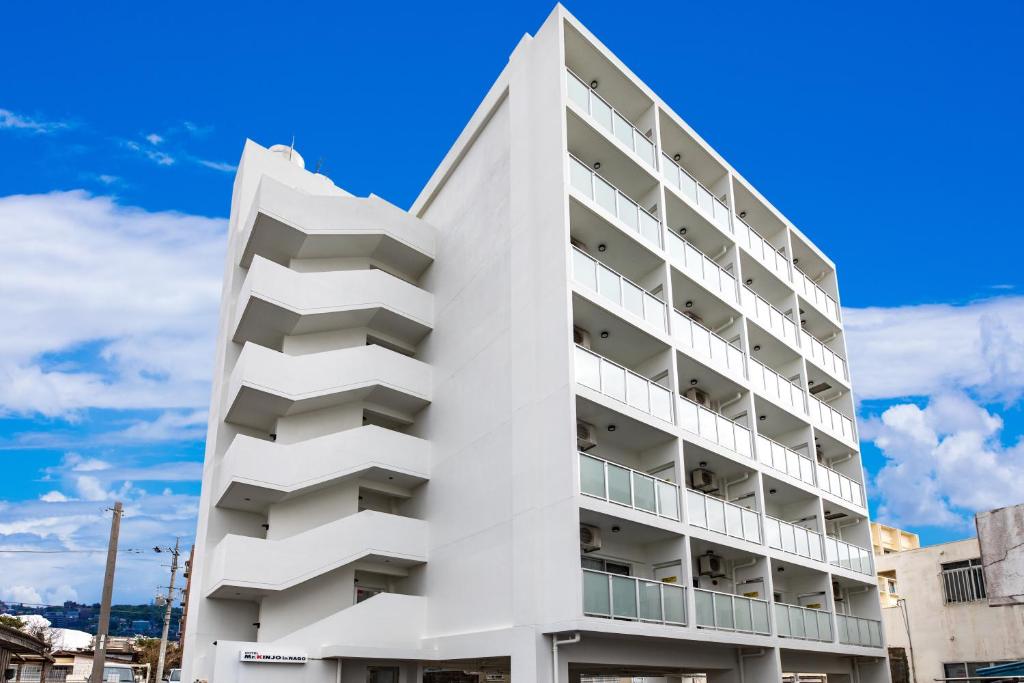 um edifício branco com varandas e um céu azul em Condominium Hotel Likka in Nago em Nago