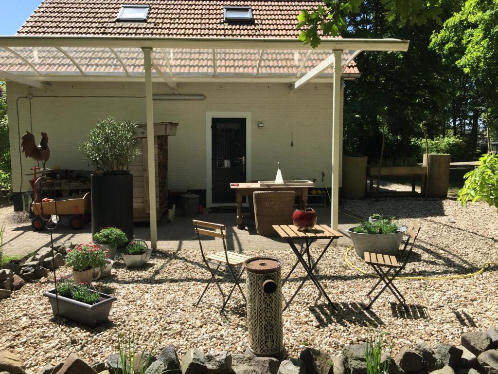 un patio trasero con mesa, sillas y pérgola en Beej Potters en Weert