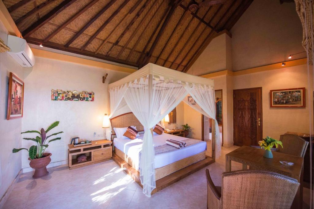 a bedroom with a bed and a desk in a room at Puri Dajuma Beach Eco-Resort & Spa in Pulukan