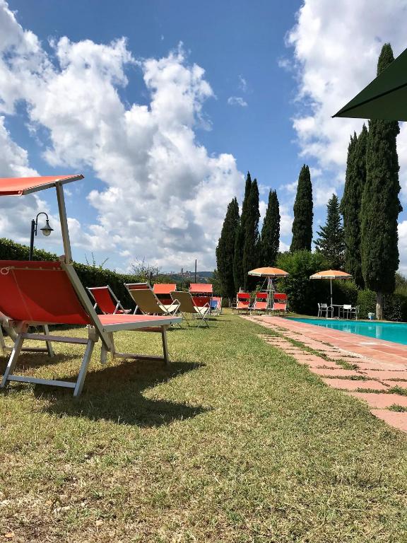 a row of lawn chairs sitting next to a pool at Podere Remignoli in San Gimignano
