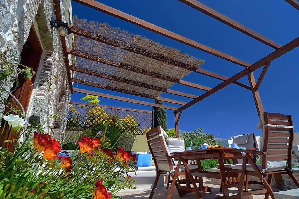 a patio with a table and chairs under a wooden pergola at Sevi's Traditional House in Kalymnos