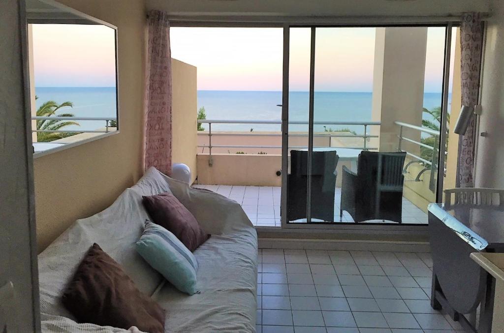 a living room with a couch and a view of the ocean at Sète - vue mer imprenable, piscine, calme in Sète