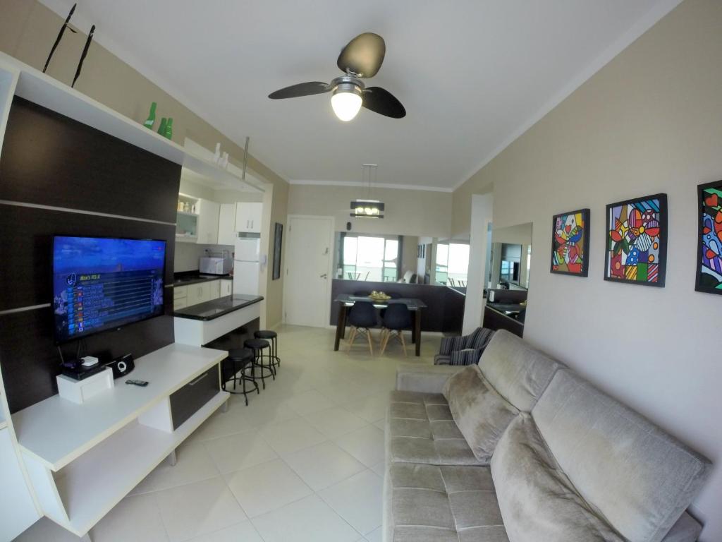 sala de estar con sofá y TV de pantalla plana en Apartamento Canasvieiras, en Florianópolis