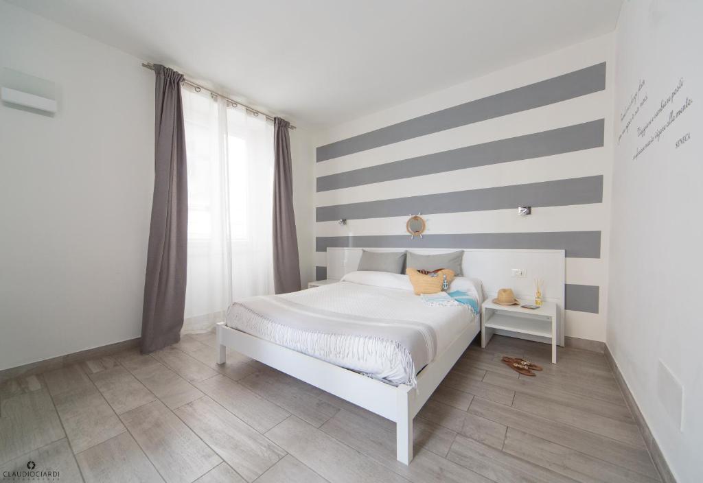 1 dormitorio con cama blanca y pared a rayas en L'Approdo Dell'Ammiraglio en La Spezia