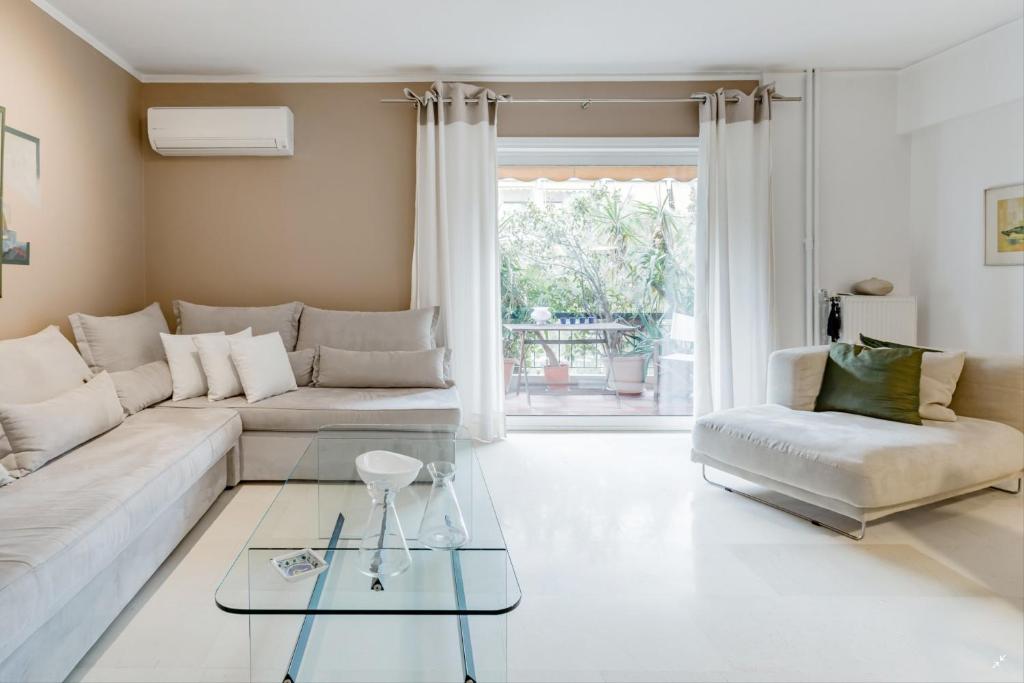 Athenian Riviera Beach Apartment في أثينا: غرفة معيشة مع أريكة بيضاء وطاولة زجاجية