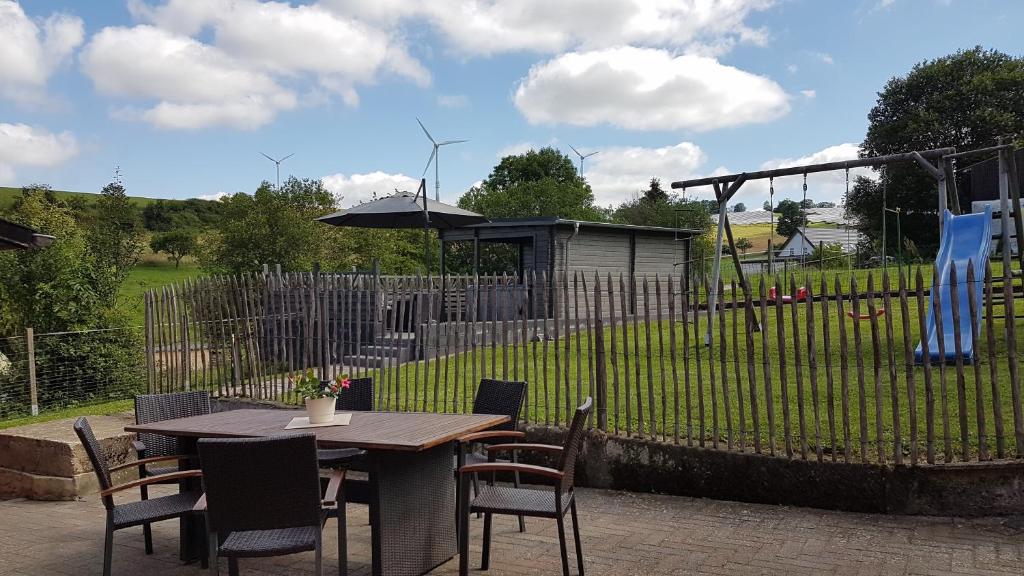 una mesa y sillas con una sombrilla en un patio en Eifel Dream Landhaus, en Plütscheid