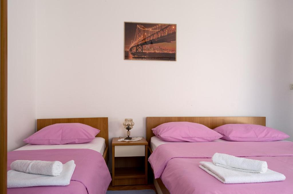 two beds in a room with pink pillows at Apartmani Marko in Makarska