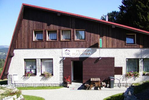 a building with a bench in front of it at Penzion Roudenka in Jestrabi V Krkonosich