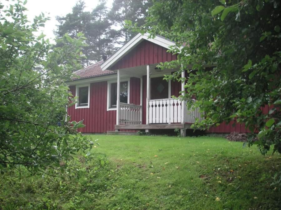 una casa roja con un porche blanco y un patio en Ängens B&B, en Sankt Anna