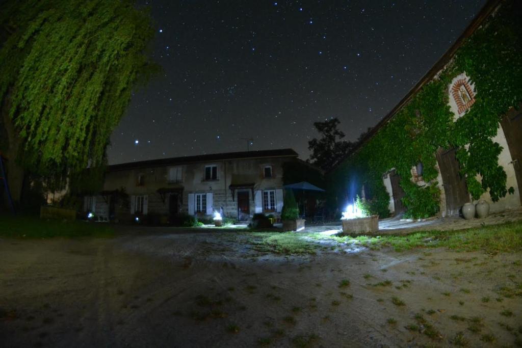 une maison avec un mur vert la nuit dans l'établissement LA FERME DU NIZON, à Valeilles