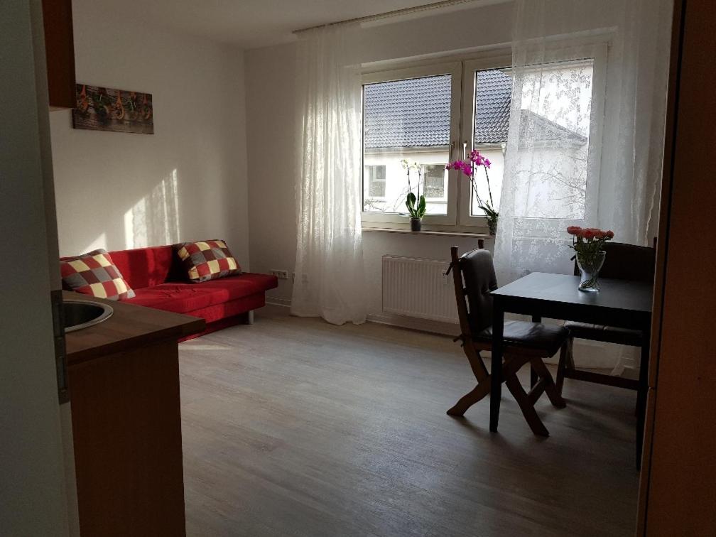 ein Wohnzimmer mit einem roten Sofa und einem Tisch in der Unterkunft Helle Ferienwohnung an der Rheinpromenade 50 qm in Duisburg