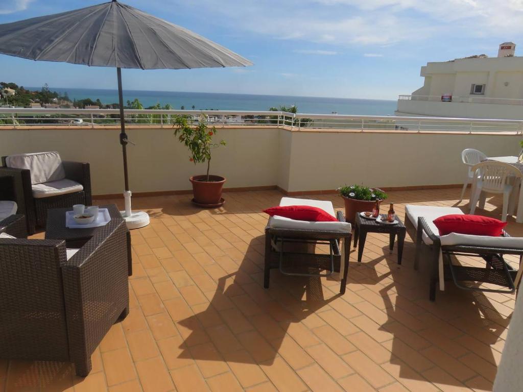 a patio with tables and chairs and an umbrella at Sweden Apartment - Top Floor one bedroom with sea views - RS in Lagos