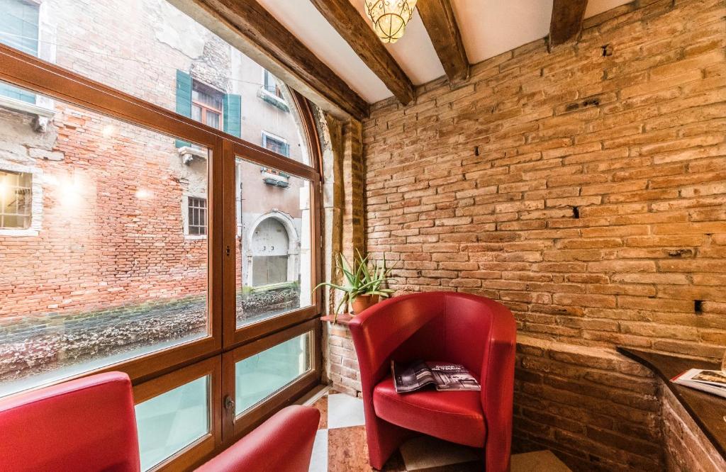 una sedia rossa in una stanza con muro di mattoni di Charme a Venise a Venezia