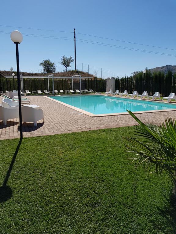 a large swimming pool with chairs and a light pole at Agriturismo Paparanza in Valguarnera Caropepe