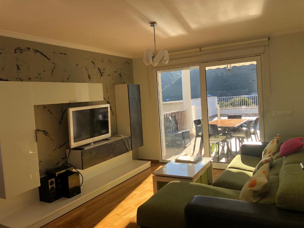 ein Wohnzimmer mit einem Sofa und einem Flachbild-TV in der Unterkunft Casa con piscina e impresionantes vistas in Gandía