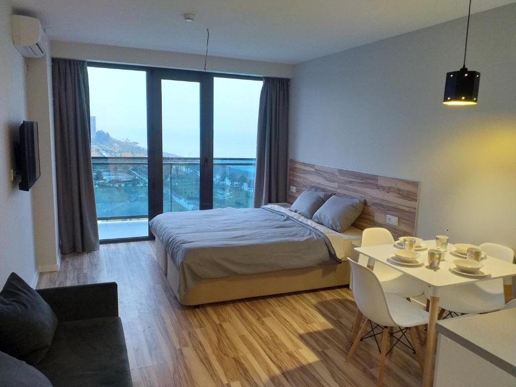 een slaapkamer met een bed en een tafel met stoelen bij BATUMI BEACH TOWER in Batoemi