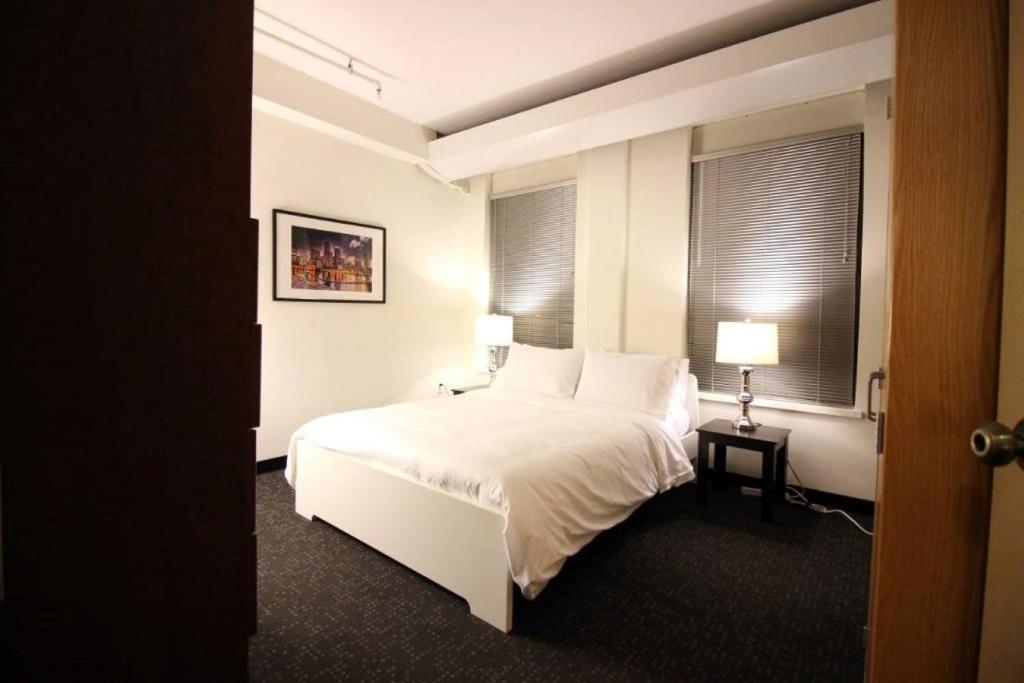 a bedroom with a white bed and two windows at Temple Place 6th Floor in Boston