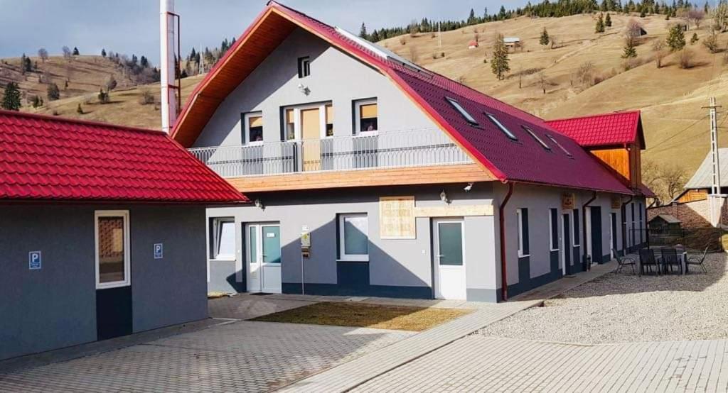 a building with a red roof on a hill at Antal Guesthouse in Ghimeş-Făget