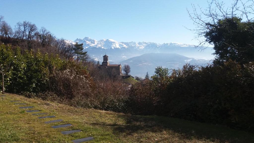 a church on a hill with mountains in the background at Rez de jardin - Calme et nature aux portes de Grenoble in Corenc