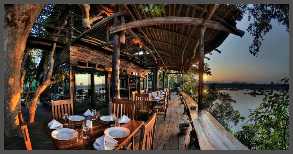 un ristorante con tavoli e sedie accanto a un fiume di Ken River Lodge a Rājgarh