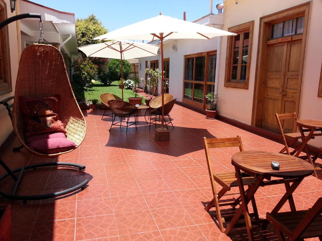 a patio with a swing and tables and chairs at La Sombra del Viento in La Serena