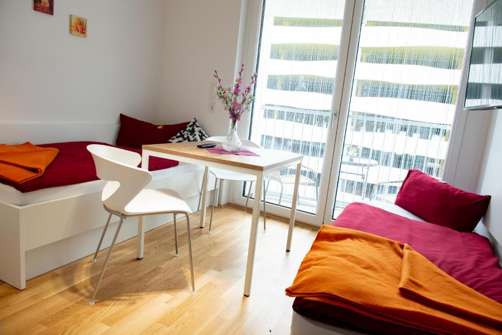 ミュンヘンにあるMyRoom - Top Munich Serviced Apartmentsのデスク、ベッド、テーブル、椅子が備わる客室です。