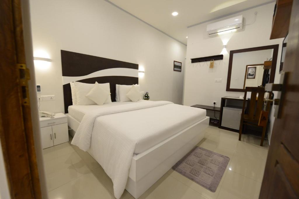 a white bedroom with a large white bed in it at Diva Villa Airport Transit Hotel in Katunayake