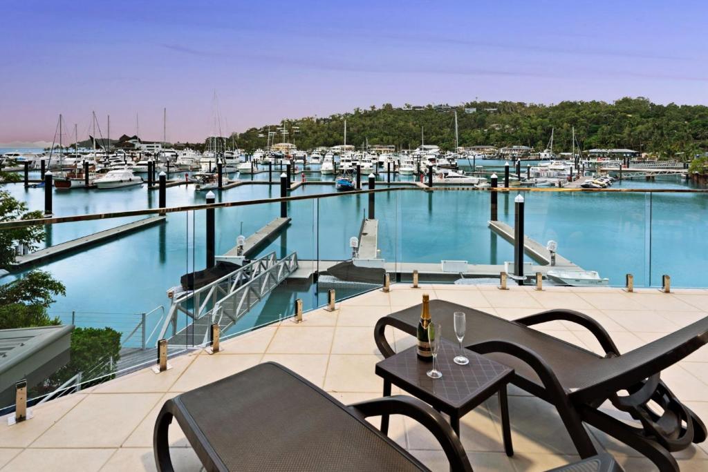 un balcone con tavolo, sedie e un porto turistico. di Pavillion 3 Absolute Waterfront 4 Bedroom 2 Lounge Room Plunge Pool + Golf Buggy a Hamilton Island
