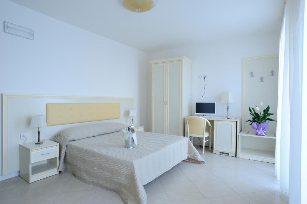 a white bedroom with a bed and a desk at Residence Suite Smeraldo in Riccione