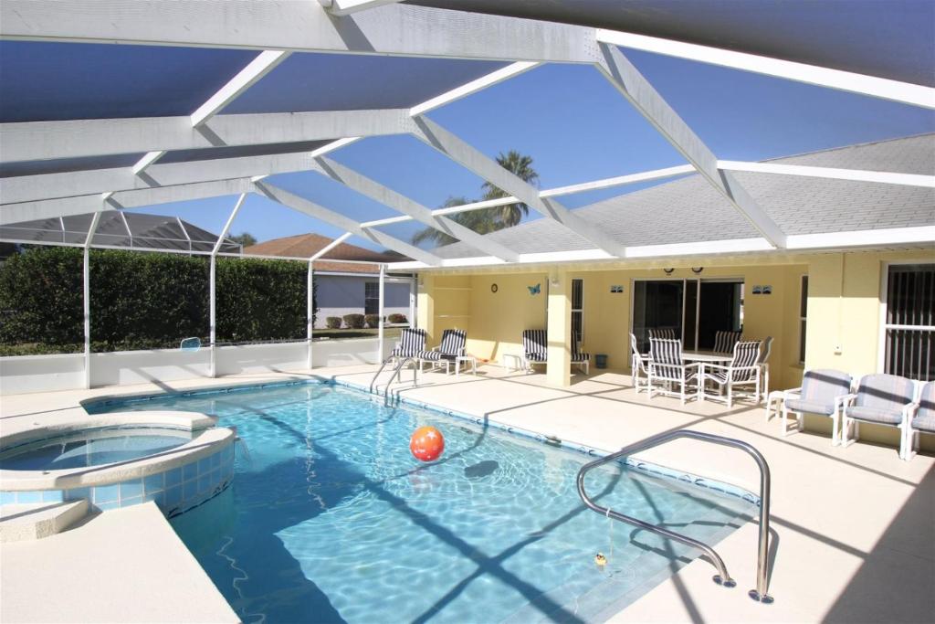 a large swimming pool with a patio with chairs and an umbrella at Villa Lovie - Family & Golf vacations in Inverness