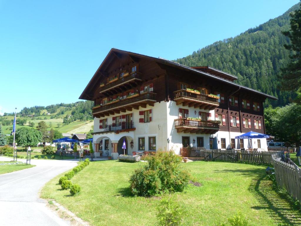 un gran edificio con un patio de césped delante de él en Hotel Schlosswirt en Großkirchheim