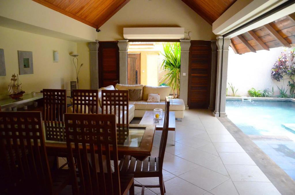 a dining room with a table and chairs and a pool at Villa Dodo in Pereybere