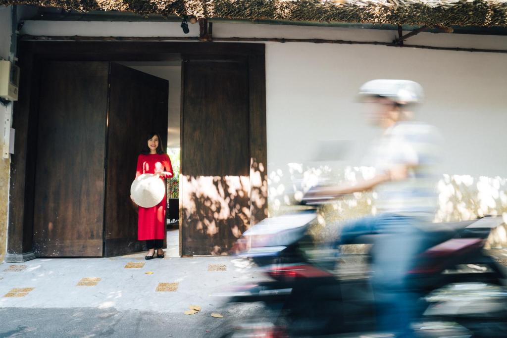 une femme en robe rouge debout sur une porte dans l'établissement IAMSAIGON homestay, à Hô-Chi-Minh-Ville