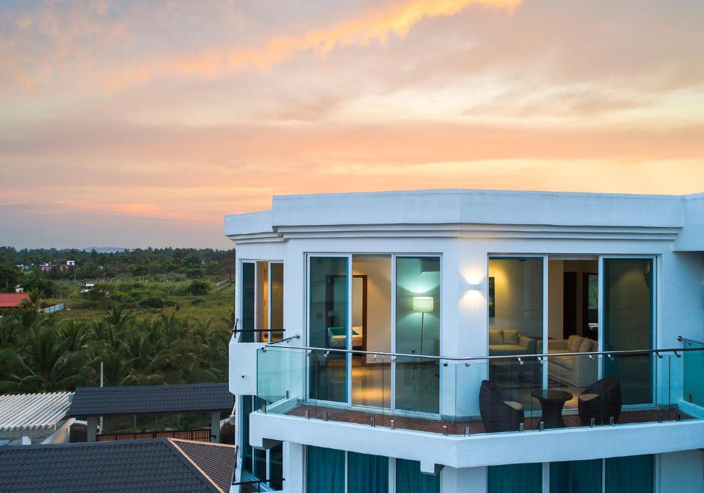 a house with a balcony with a sunset in the background at CASAMIA Oceanfront Condos Nilaveli in Nilaveli