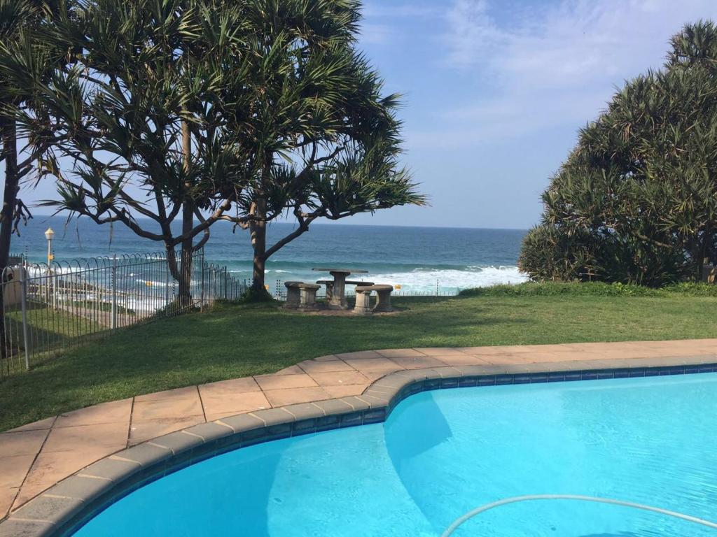 - une piscine avec une table de pique-nique et l'océan dans l'établissement 9 Casablance Ballito~Beach on your doorstep., à Ballito