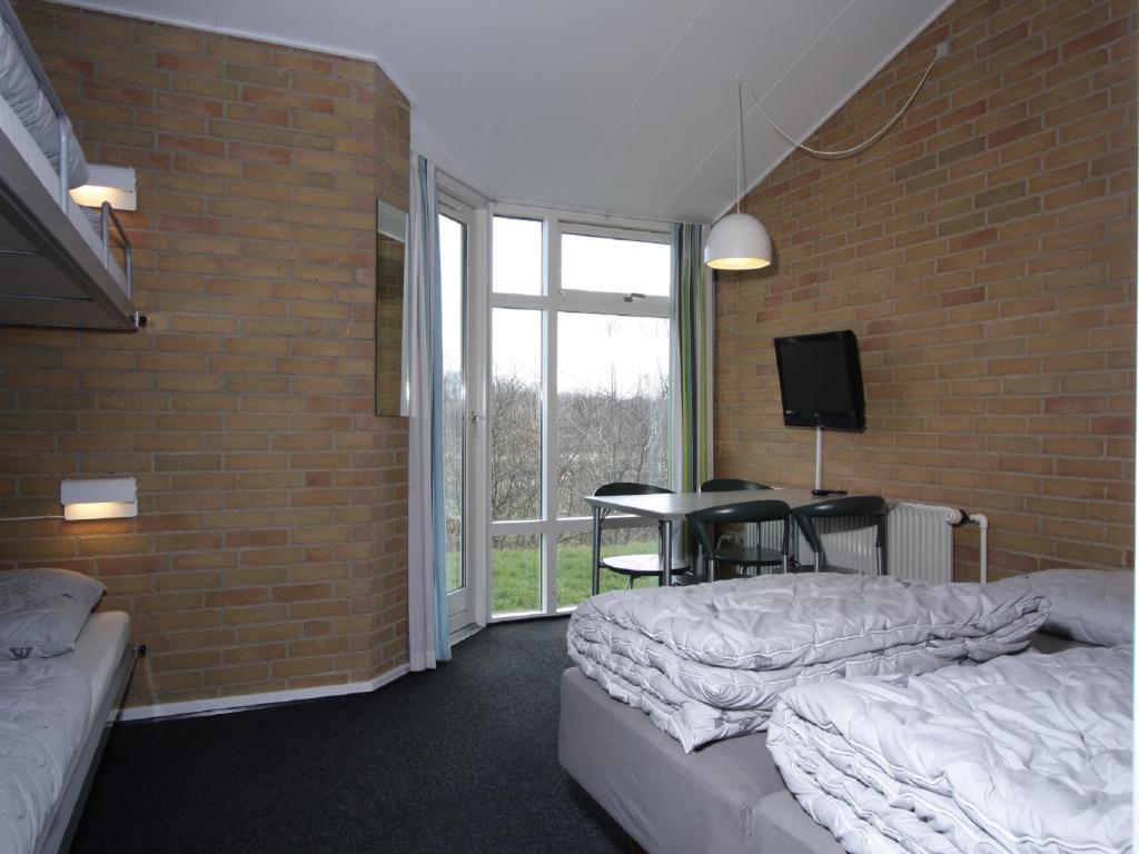 Zimmer mit 2 Betten, einem Tisch und einer Ziegelwand in der Unterkunft Danhostel Fredericia in Fredericia