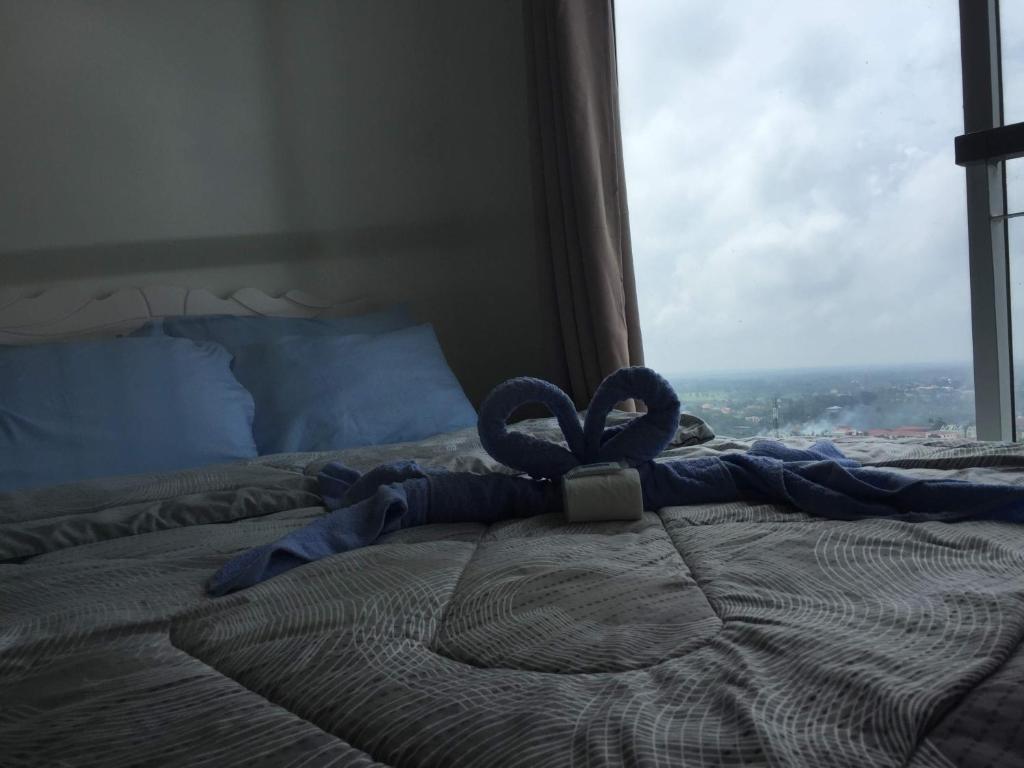 Bett mit blauem Band und Fenster in der Unterkunft Wind Residences Tower 3 4 5 by SMCo in Tagaytay