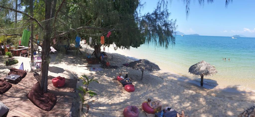 a beach with people sitting on the sand and the water at Sabai Sabai Beach Bungalows in Ko Phayam