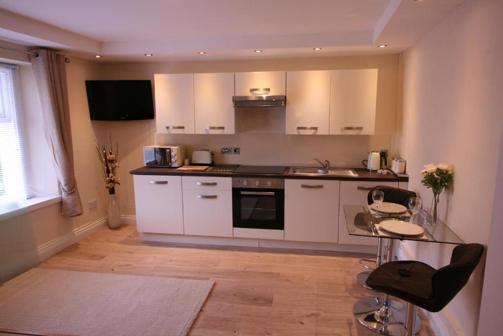 a kitchen with white cabinets and a table and chairs at The Thomas Suite in Llandudno