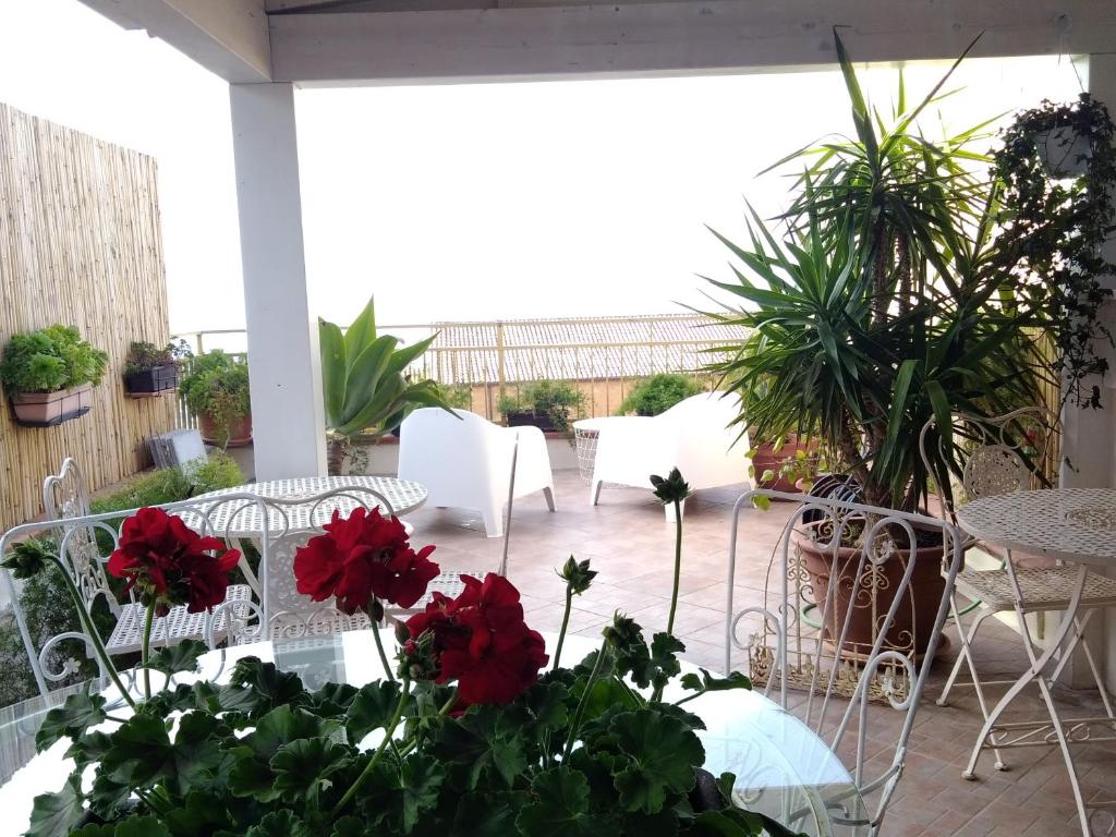 un patio con tavoli, sedie e fiori rossi di B&B Portatenea a Agrigento