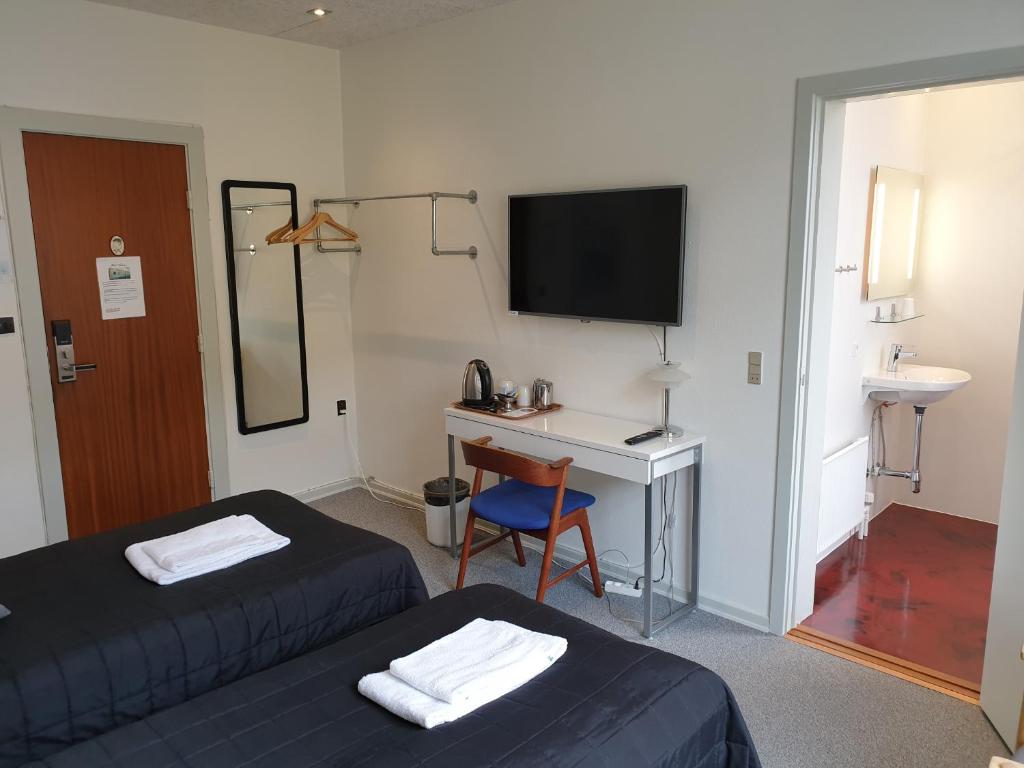 a room with two beds and a desk and a television at Hotel Aabenraa in Aabenraa