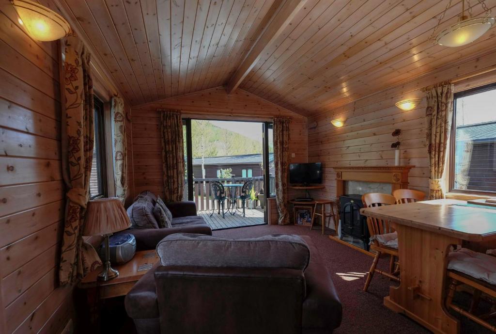 una sala de estar con sofá y mesa en una cabaña en Fellside Lodge, en Keswick