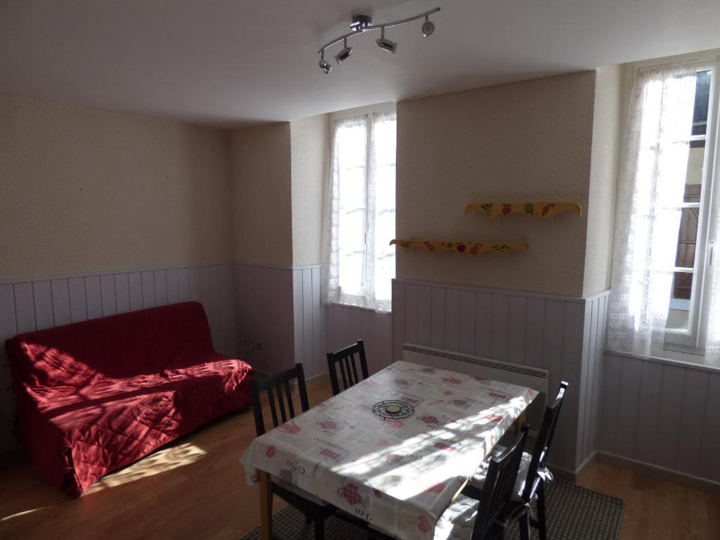 a dining room with a table and a red couch at Appartement de la cascade in Eaux-Bonnes