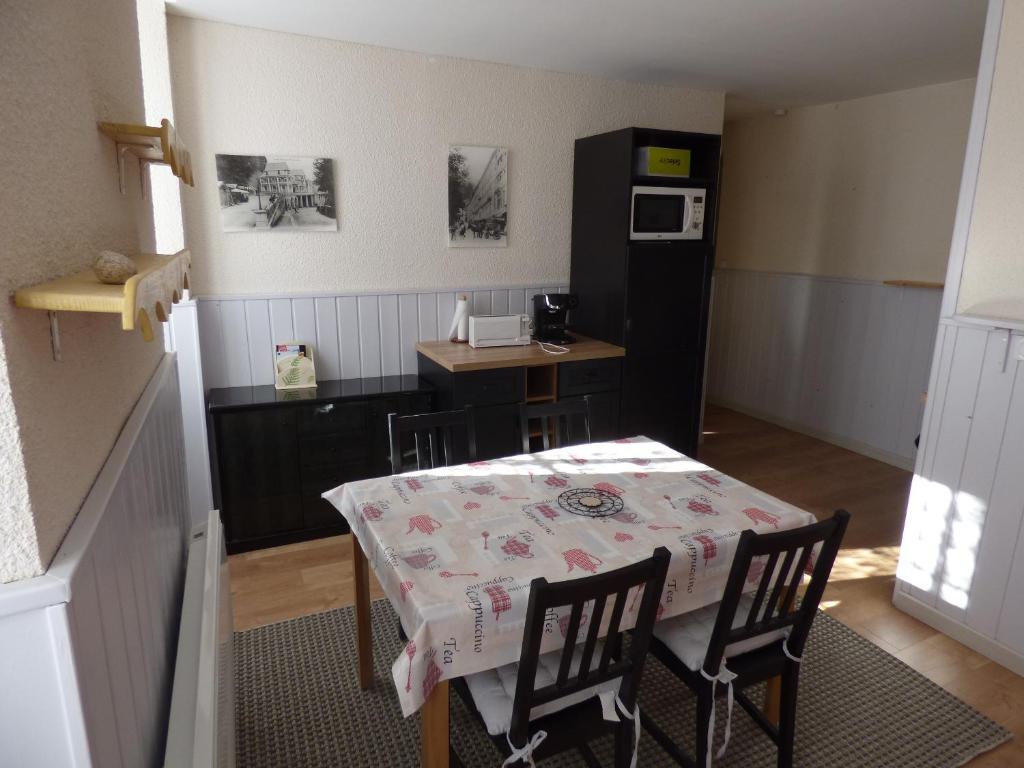 a kitchen with a table and chairs and a kitchen with a refrigerator at Appartement de la cascade in Eaux-Bonnes