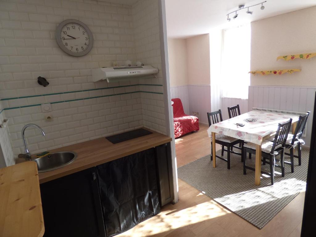 a kitchen with a table and a clock on the wall at Appartement de la cascade in Eaux-Bonnes