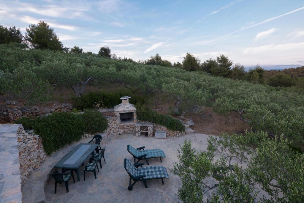a patio with picnic tables and a fireplace on a hill at Olive Tree House - Charme Homes in Sutivan