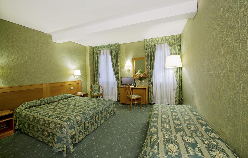 a hotel room with two beds and a desk at Hotel Nazionale in Venice
