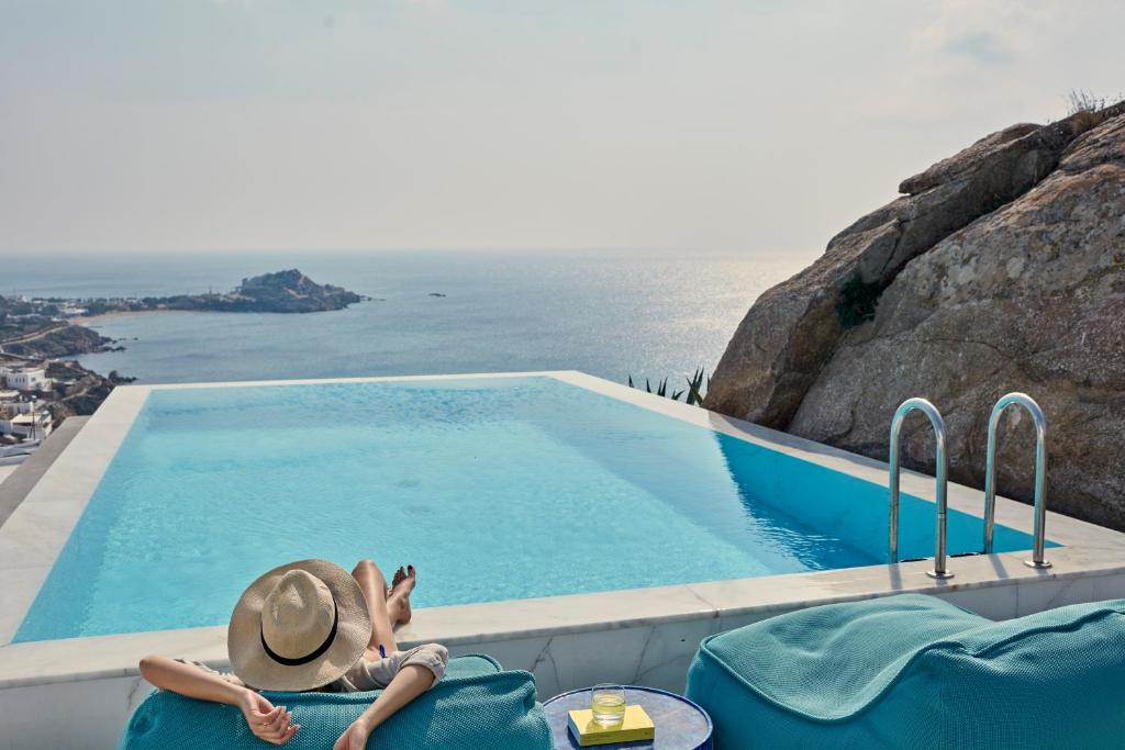 a woman laying on a chair next to a swimming pool at Myconian Ambassador Relais & Chateaux in Platis Gialos